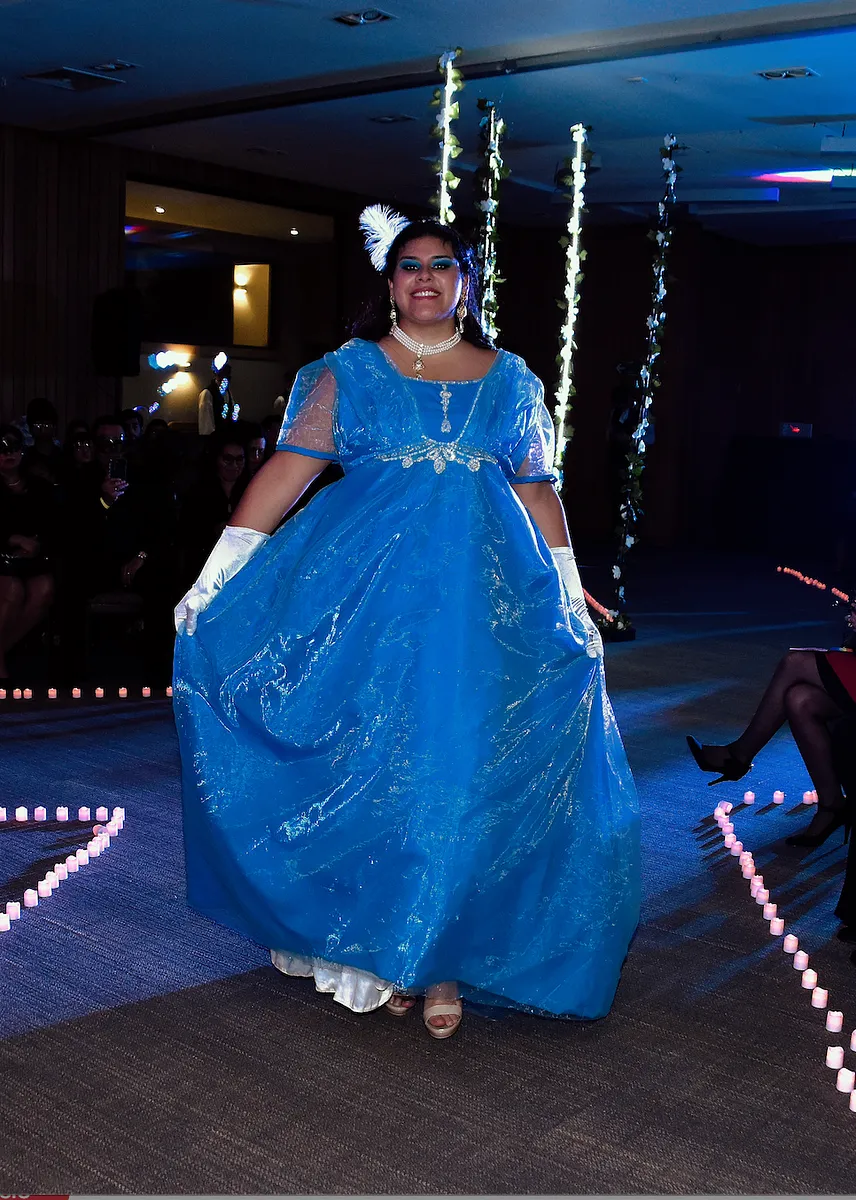 Celesta en azul intenso, con cintura alta, mangas transparentes y falda de gran volumen durante una presentación.