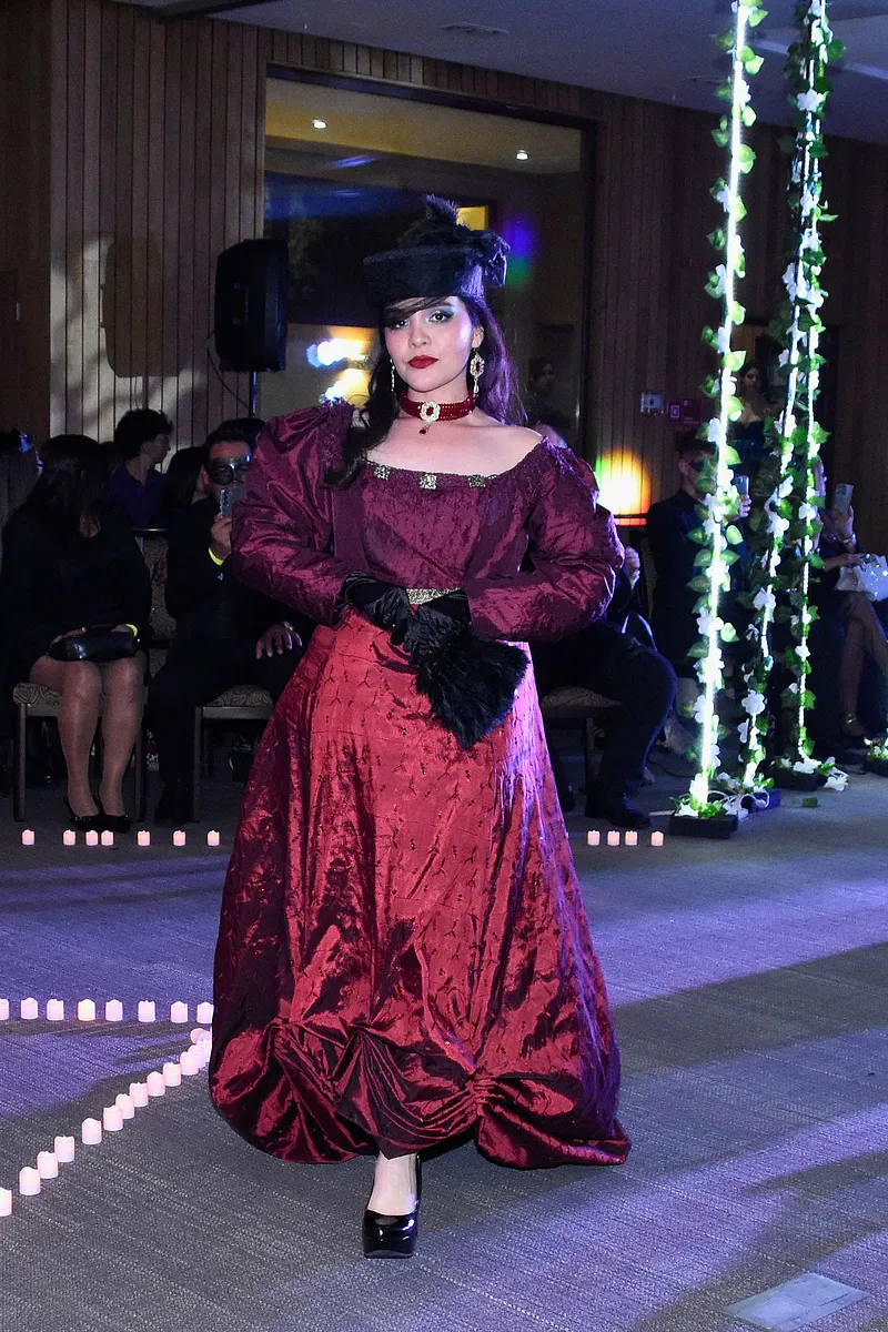 Karenina en borgoña, con mangas amplias, falda estructurada, guantes negros y sombrero para una atmósfera rusa romántica.