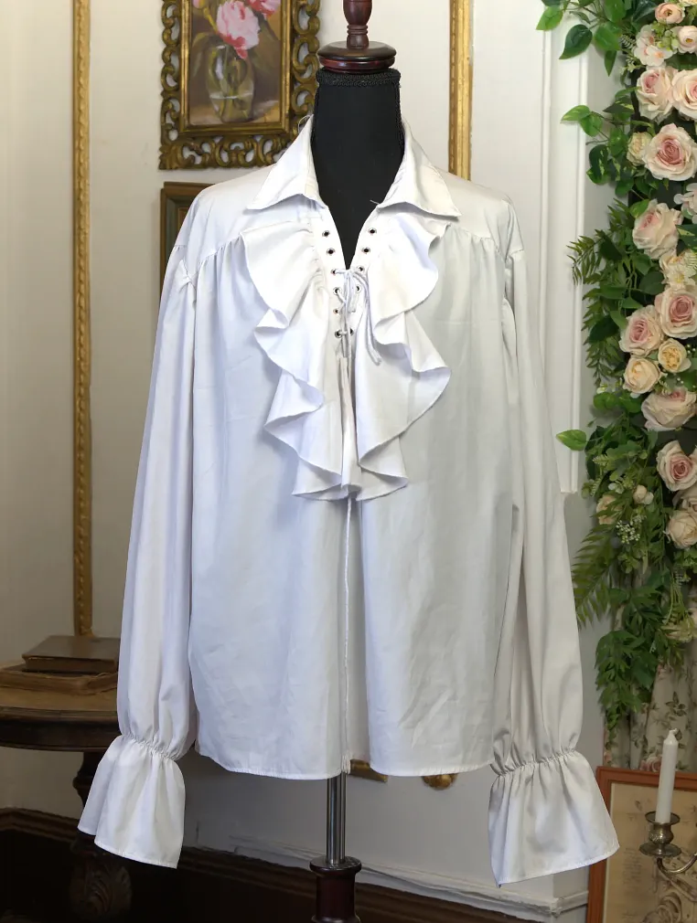Blusa blanca suelta en maniquí, con cuello abierto, cordón frontal, vuelos en el pecho y mangas amplias terminadas en puños fruncidos.